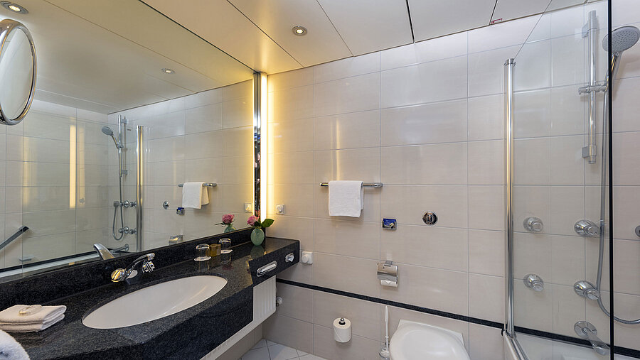 Modern bathroom at Maritim Hotel Frankfurt with large mirror, stylish sink, and shower-bathtub.
