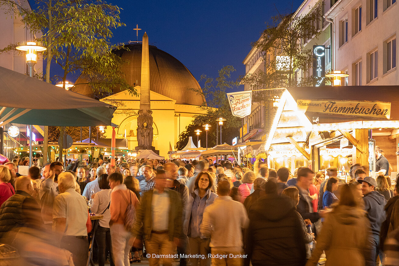 Busy city festival with market stalls and church at night
