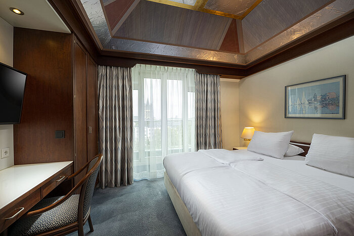 Family room at Maritim Hotel Cologne with a comfortable double bed, desk, and view of Cologne Cathedral.
