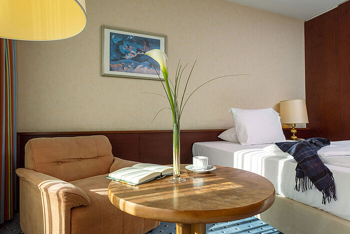 Comfort room at Maritim Hotel Cologne with a cozy armchair, side table, single bed, and modern decorative elements.