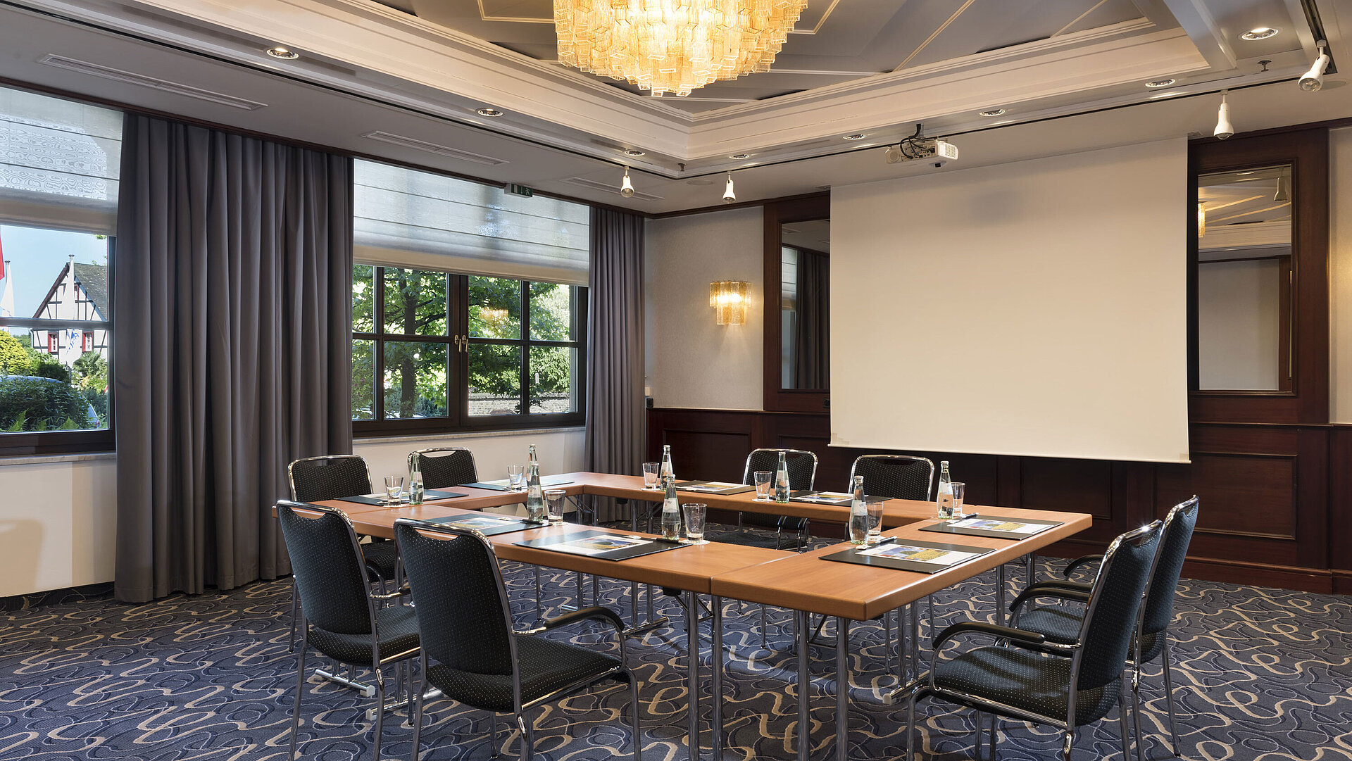 Bright meeting room with modern technology, large windows, and elegant chandelier at Maritim Hotel Königswinter.