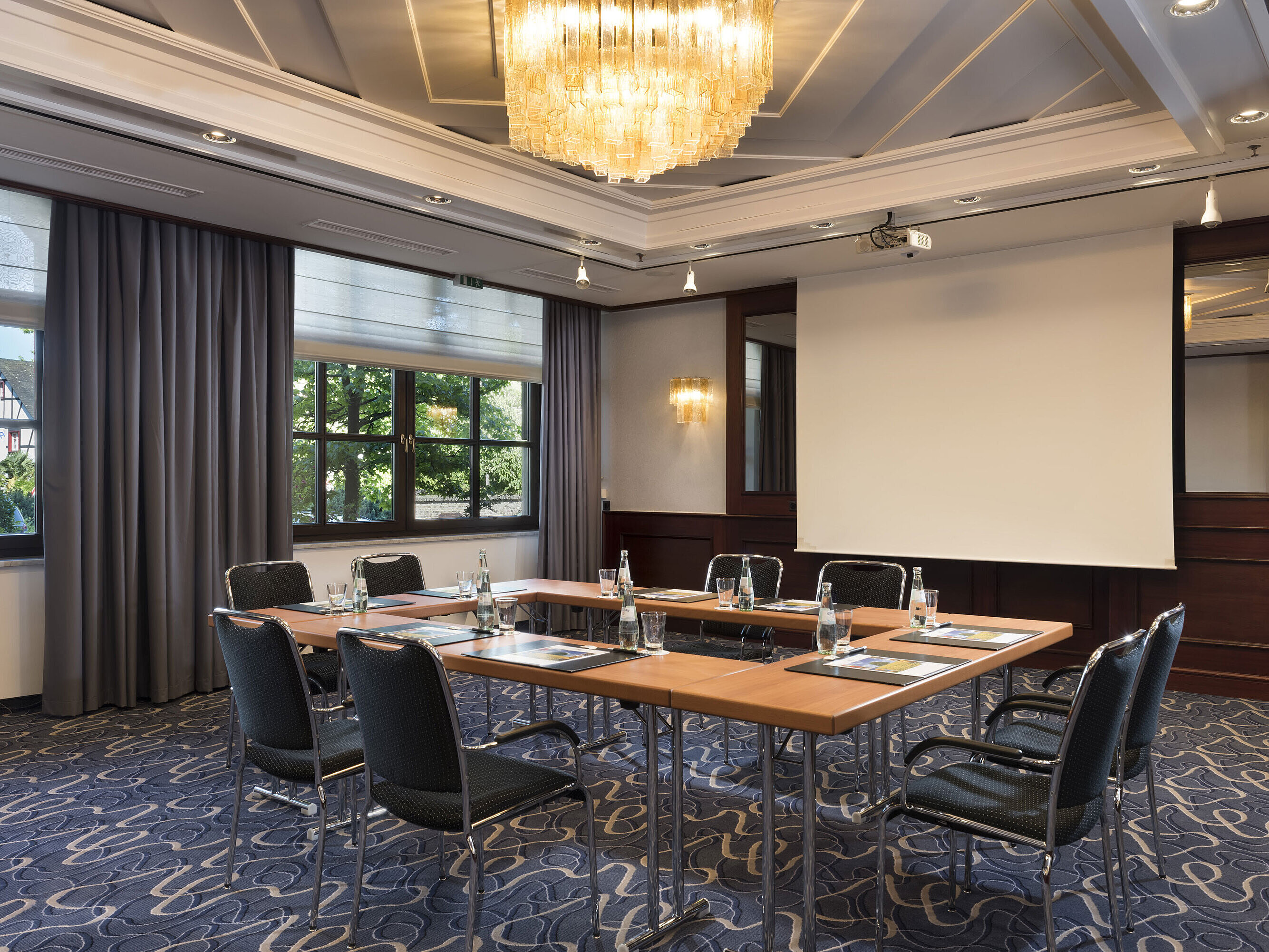 Bright meeting room with modern technology, large windows, and elegant chandelier at Maritim Hotel Königswinter.