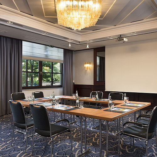 Bright meeting room with modern technology, large windows, and elegant chandelier at Maritim Hotel Königswinter.