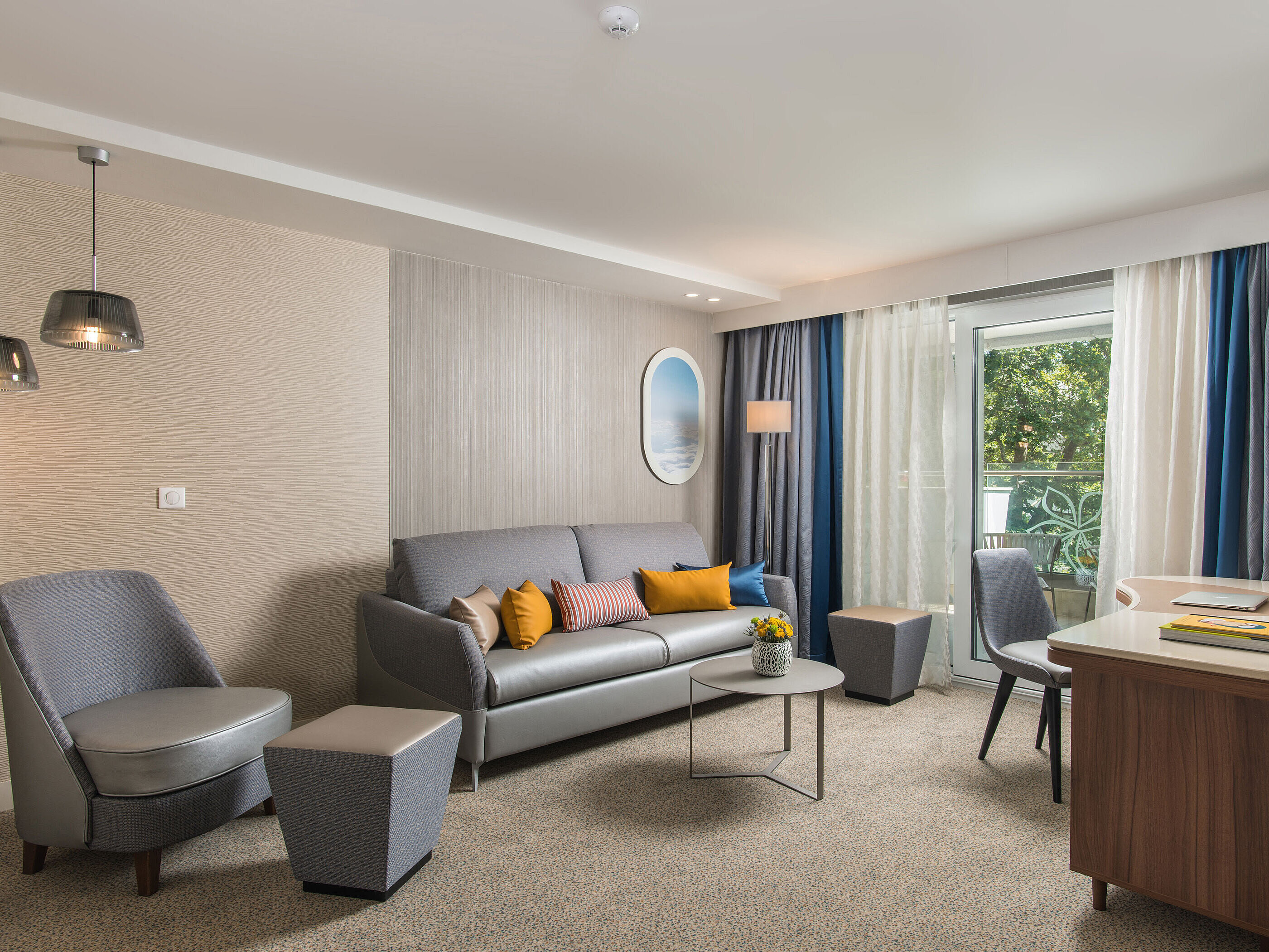 Modern room at Maritim Hotel Amelia with cosy seating area, sofa and balcony overlooking greenery