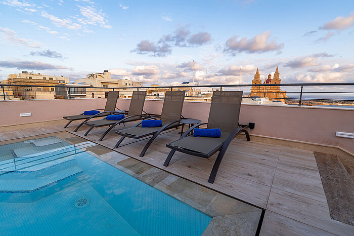 Modern rooftop pool with sun loungers and panoramic city views