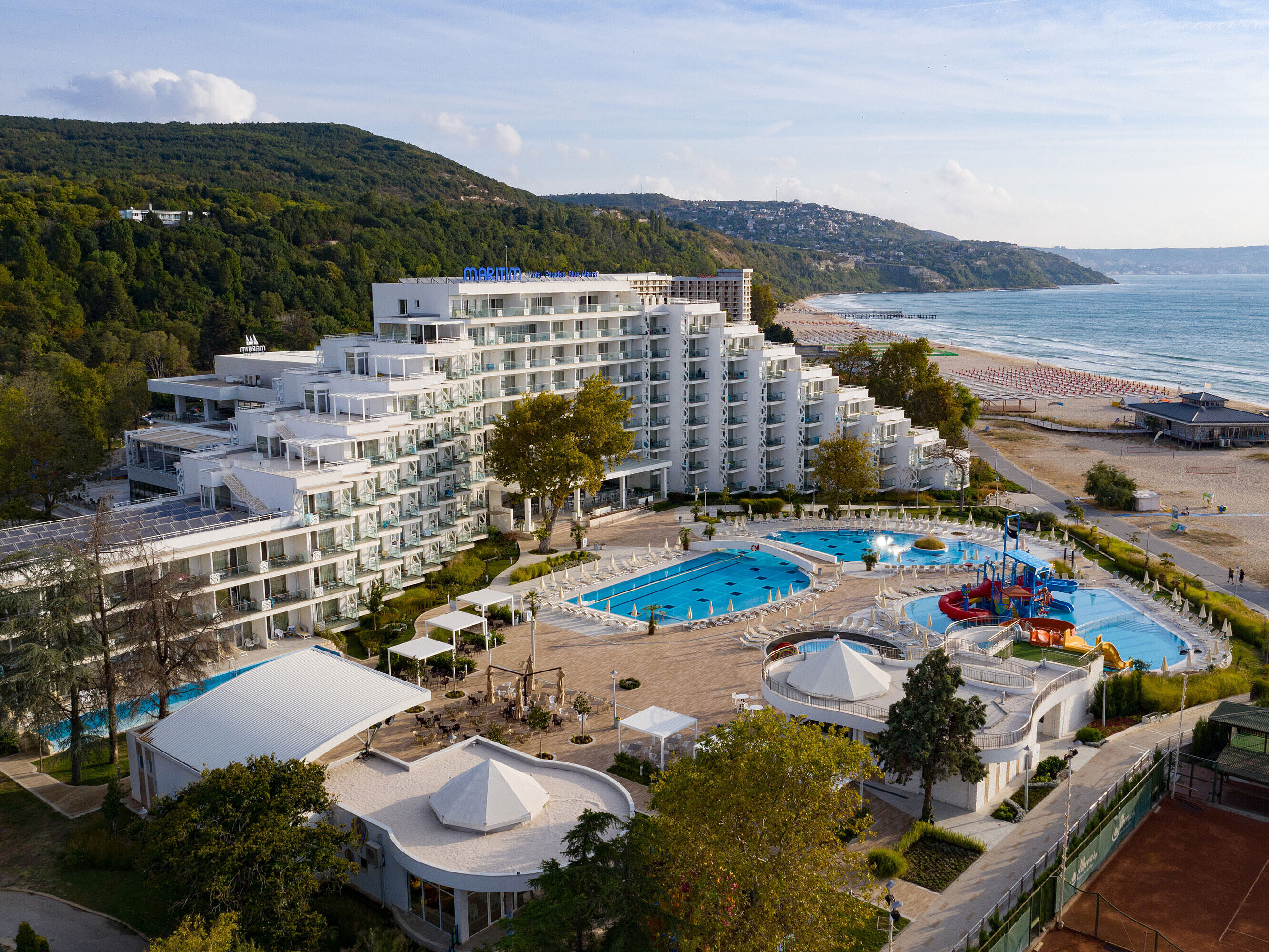 Aerial view of the resort with pools, beach, modern hotel building and coastline