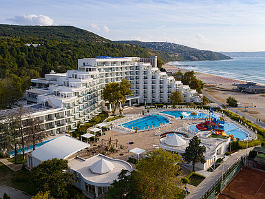 Aerial view of the resort with pools, beach, modern hotel building and coastline