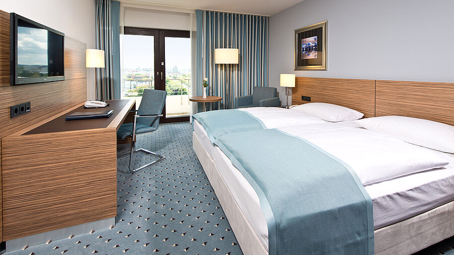 Comfort room at Maritim Hotel Darmstadt with modern design, desk, cozy seating area, and large windows.