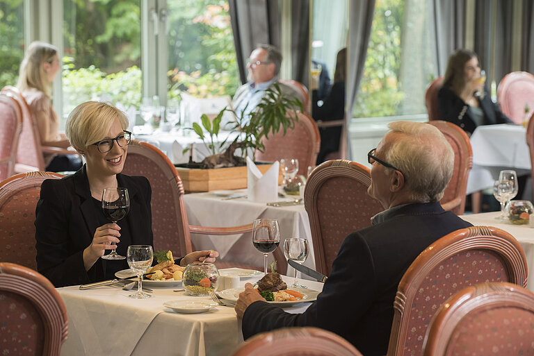 Guests dining at the stylish restaurant of Maritim Hotel Bad Salzuflen with garden view