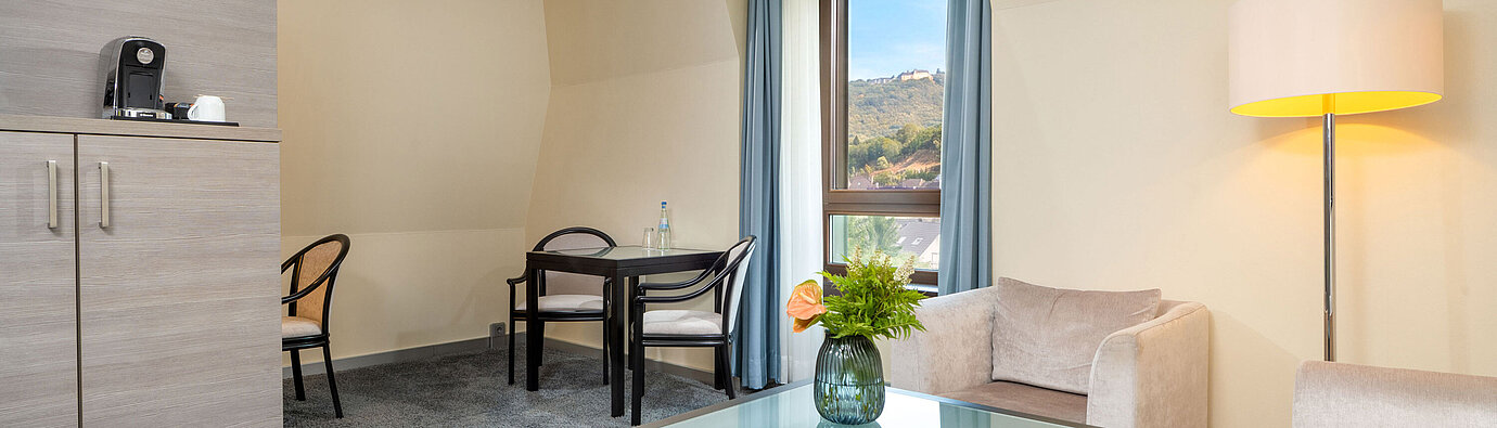 Living area of the Junior Suite at Maritim Hotel Königswinter with seating, coffee table and window.