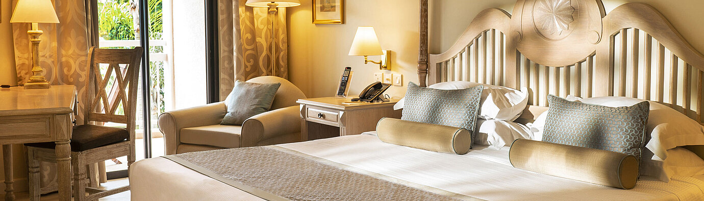 Suite with four-poster bed, seating area and open bathroom concept at Maritim Hotel