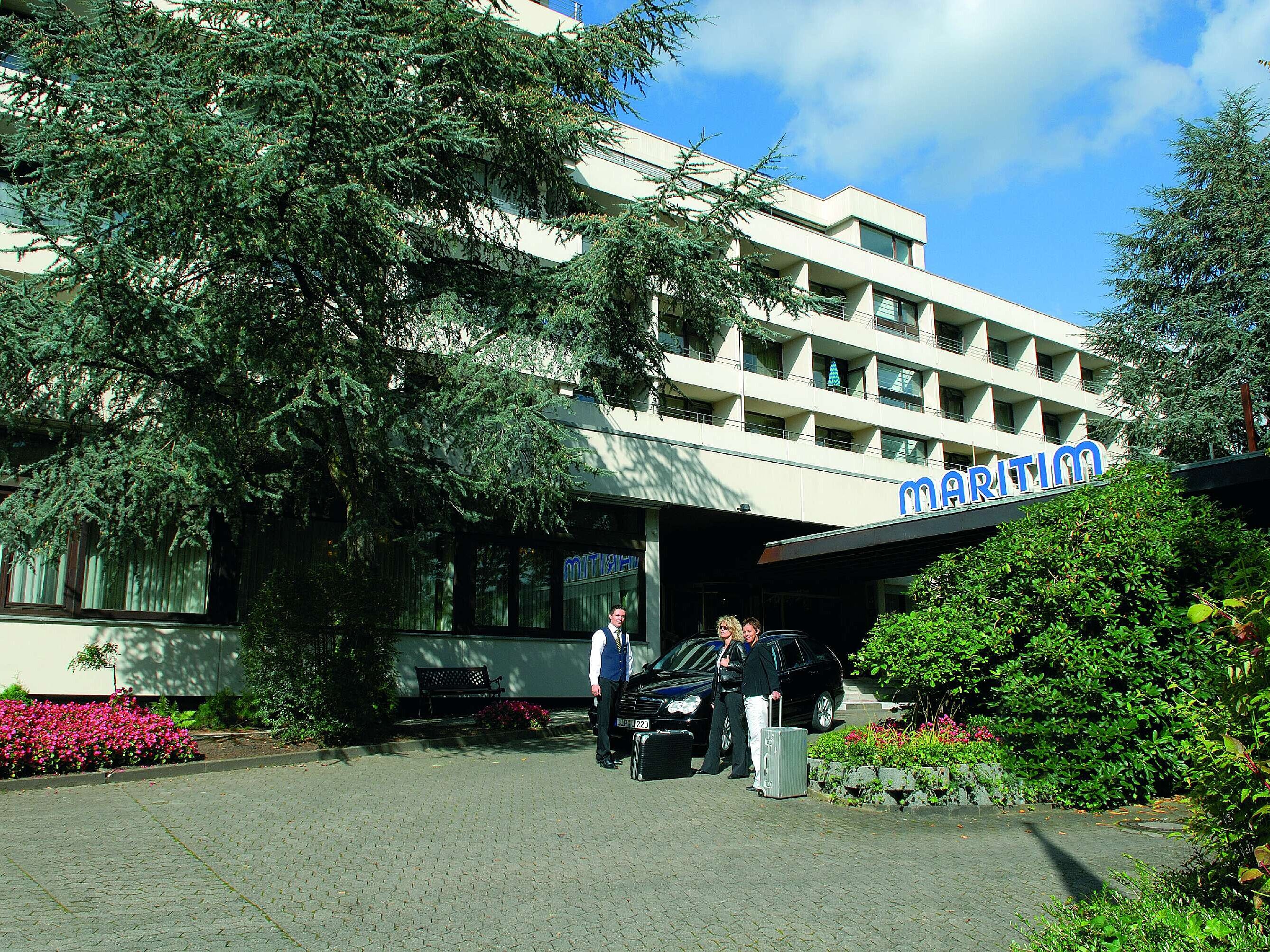 Guests arrive at Maritim Hotel Bad Salzuflen surrounded by trees and landscaped greenery