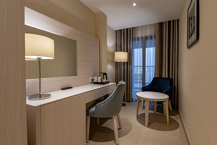 Modern workspace with desk, mirror, armchair and seating area in a stylish hotel room