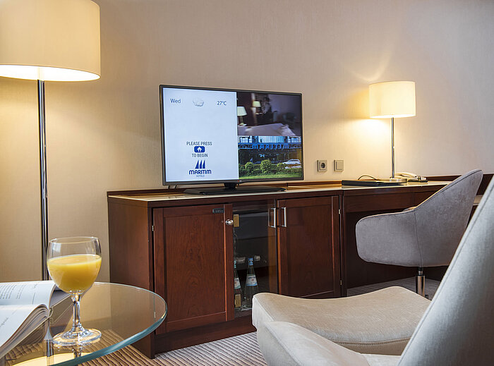 Detail of a room at Maritim Hotel Bonn with TV, desk, and glass of orange juice on the table.