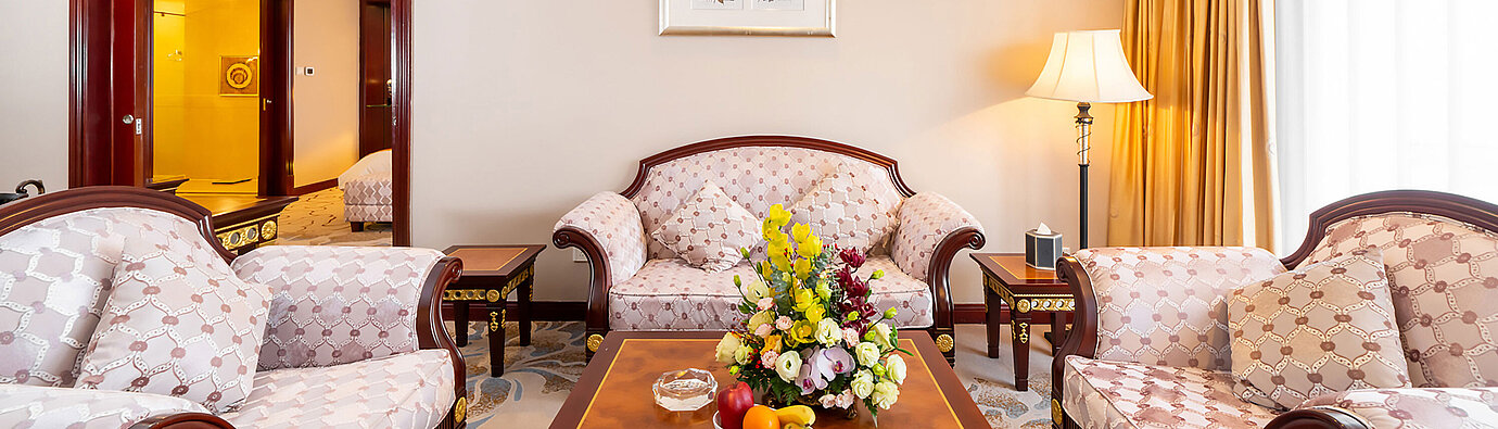 經典休憩區配有三張軟墊座椅、大型木質餐桌、花卉擺設及暖意盎然的窗邊光線