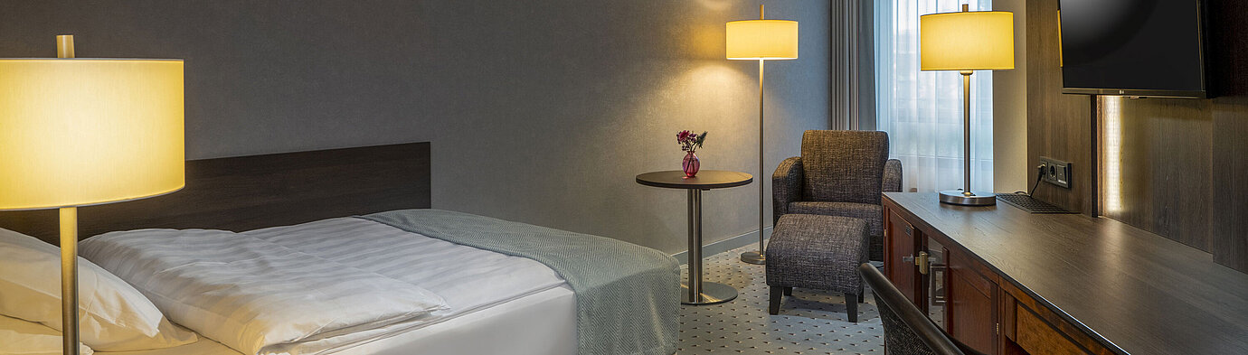 Modernly furnished Classic room with desk, TV, seating area, and comfortable bed at Maritim Hotel Bremen.