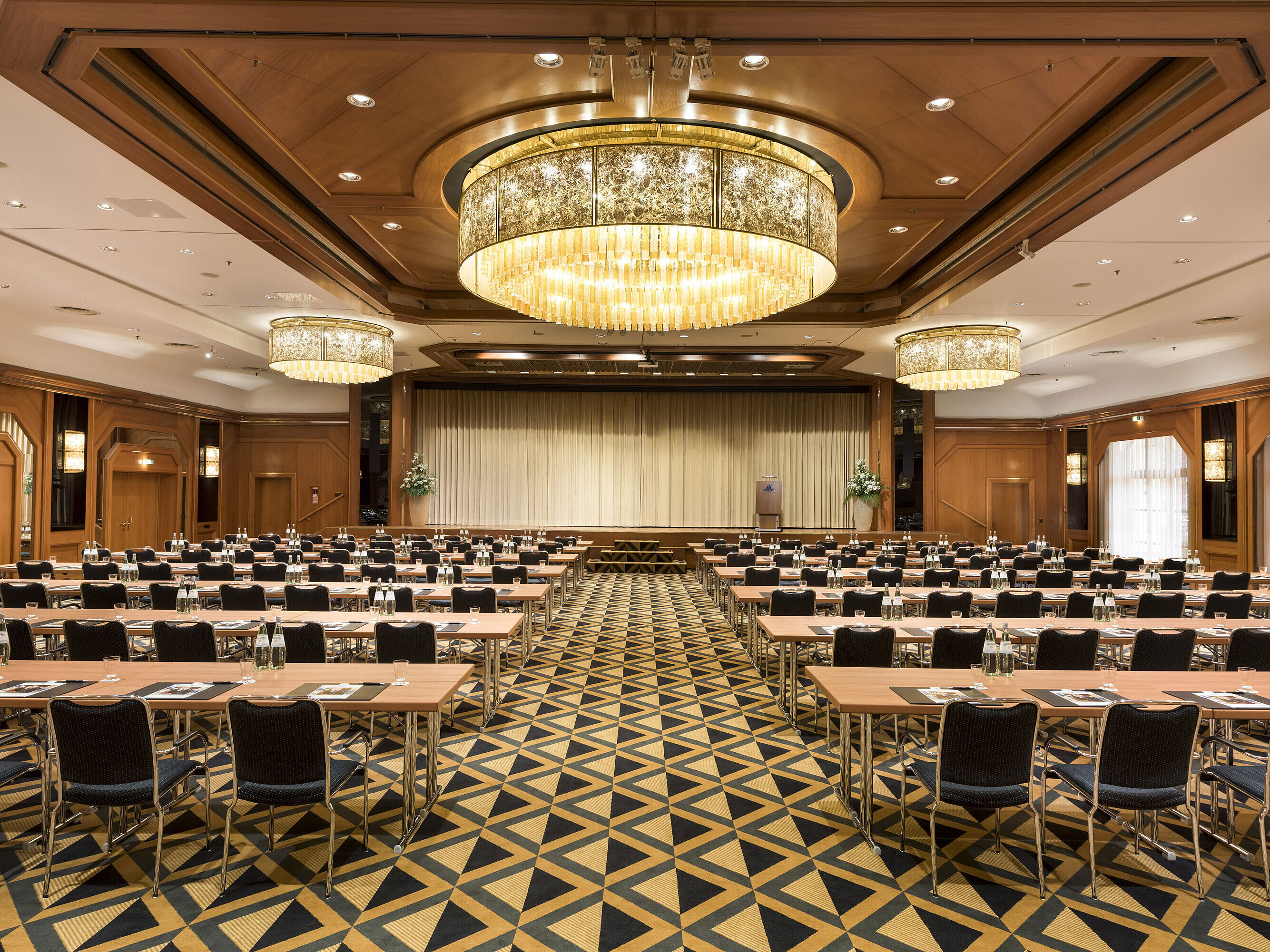 Elegant conference hall with stage, chandeliers, and modern seating at Maritim Hotel Königswinter.
