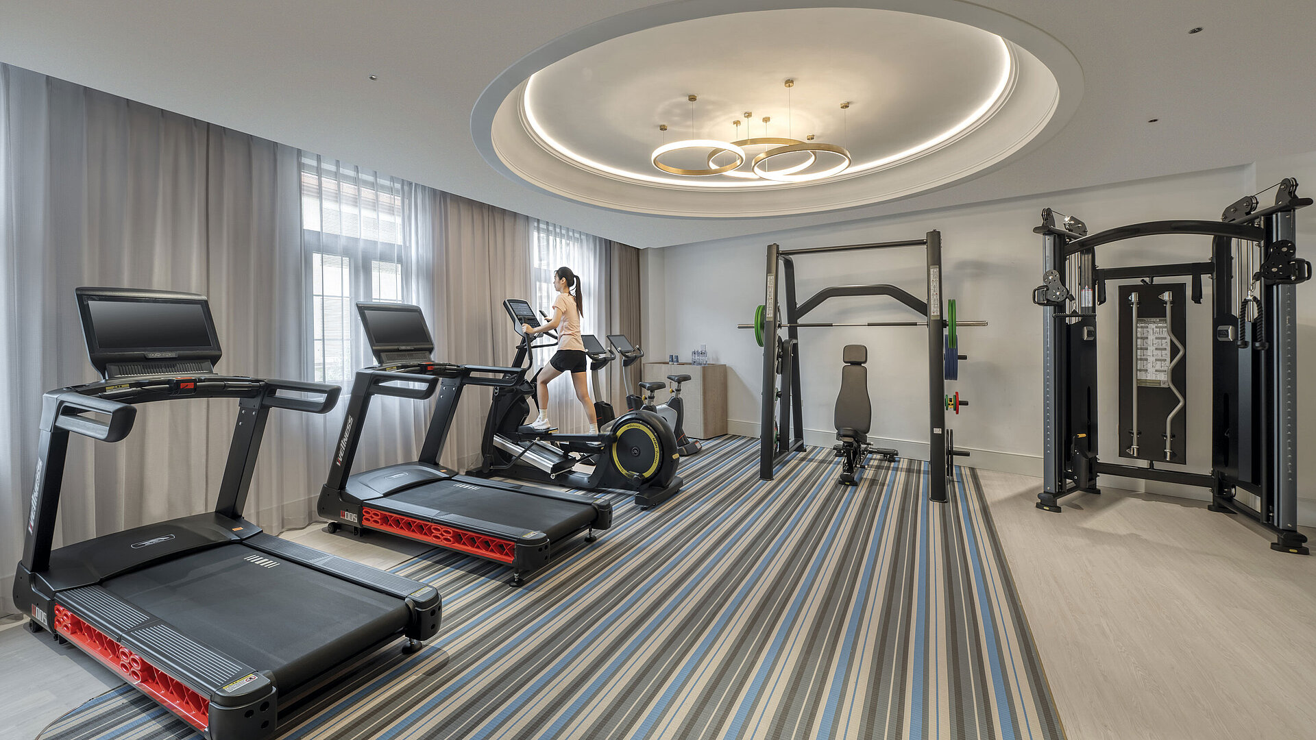 Modern hotel fitness room with treadmills, strength equipment and natural daylight