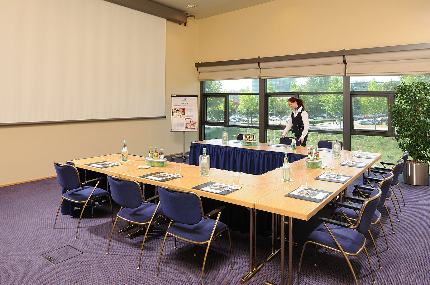 Meeting room in Maritim Hotel Dresden with U-shaped table setup, presentation screen, and meeting preparations.