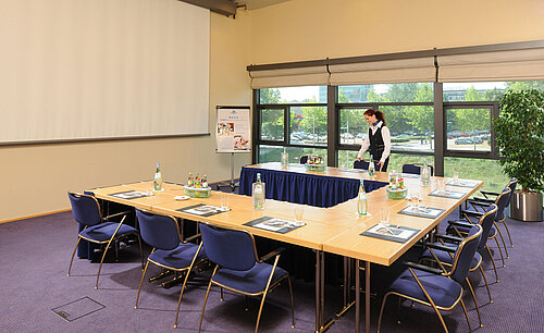 Meeting room in Maritim Hotel Dresden with U-shaped table setup, presentation screen, and meeting preparations.