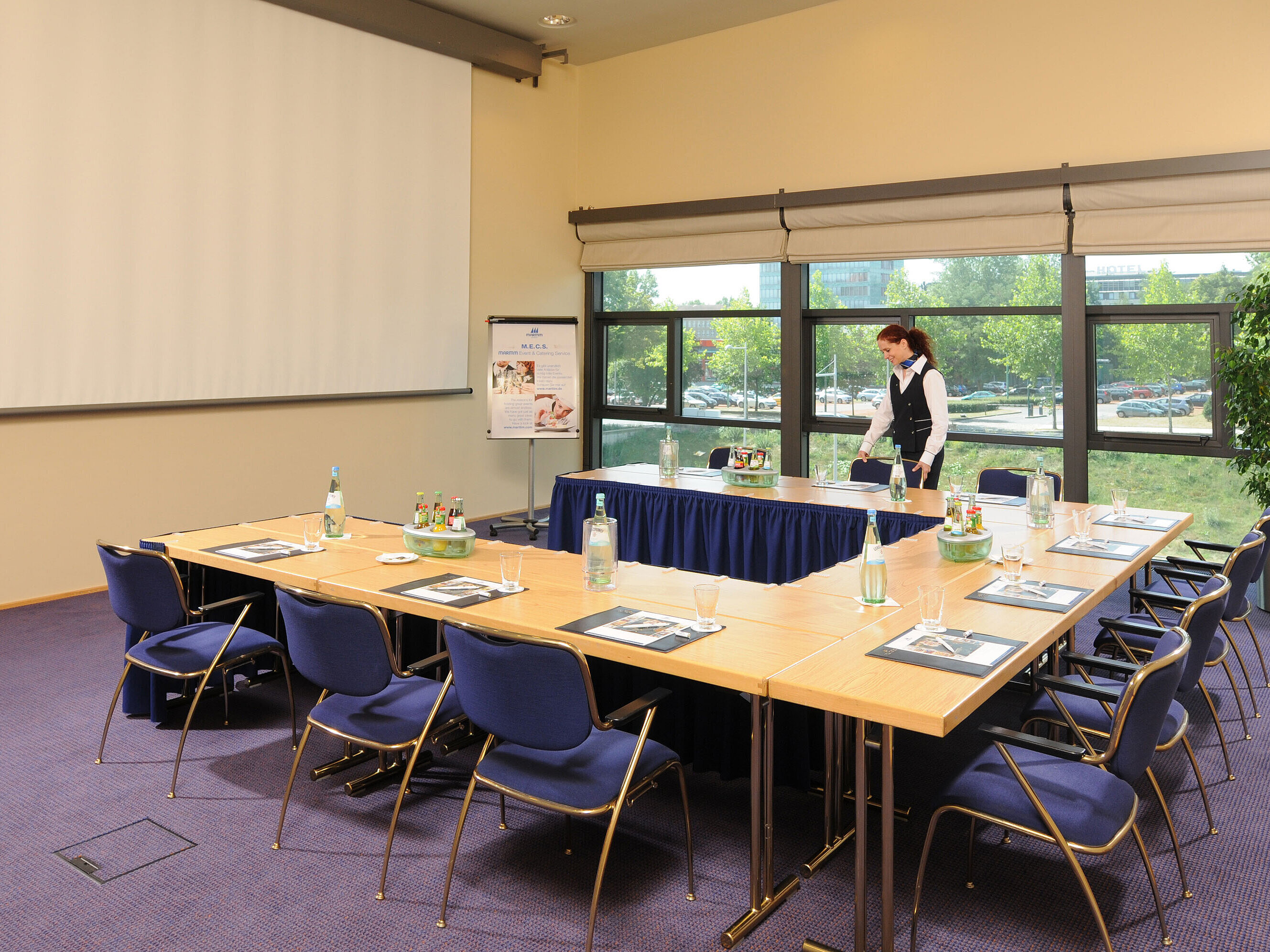 Meeting room in Maritim Hotel Dresden with U-shaped table setup, presentation screen, and meeting preparations.