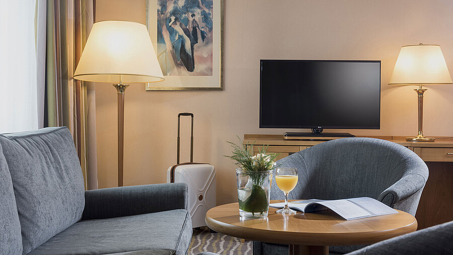 Comfortable hotel room with a desk, flat-screen TV, seating area with natural light, and stylish interior.