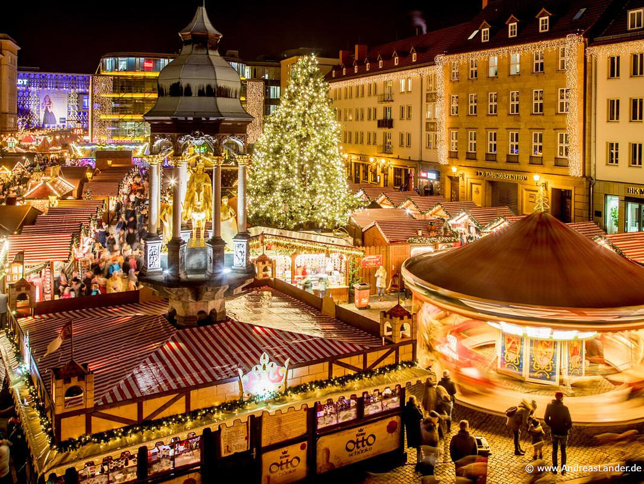 Christmas market in Magdeburg with illuminated stalls, carousel and large Christmas tree.