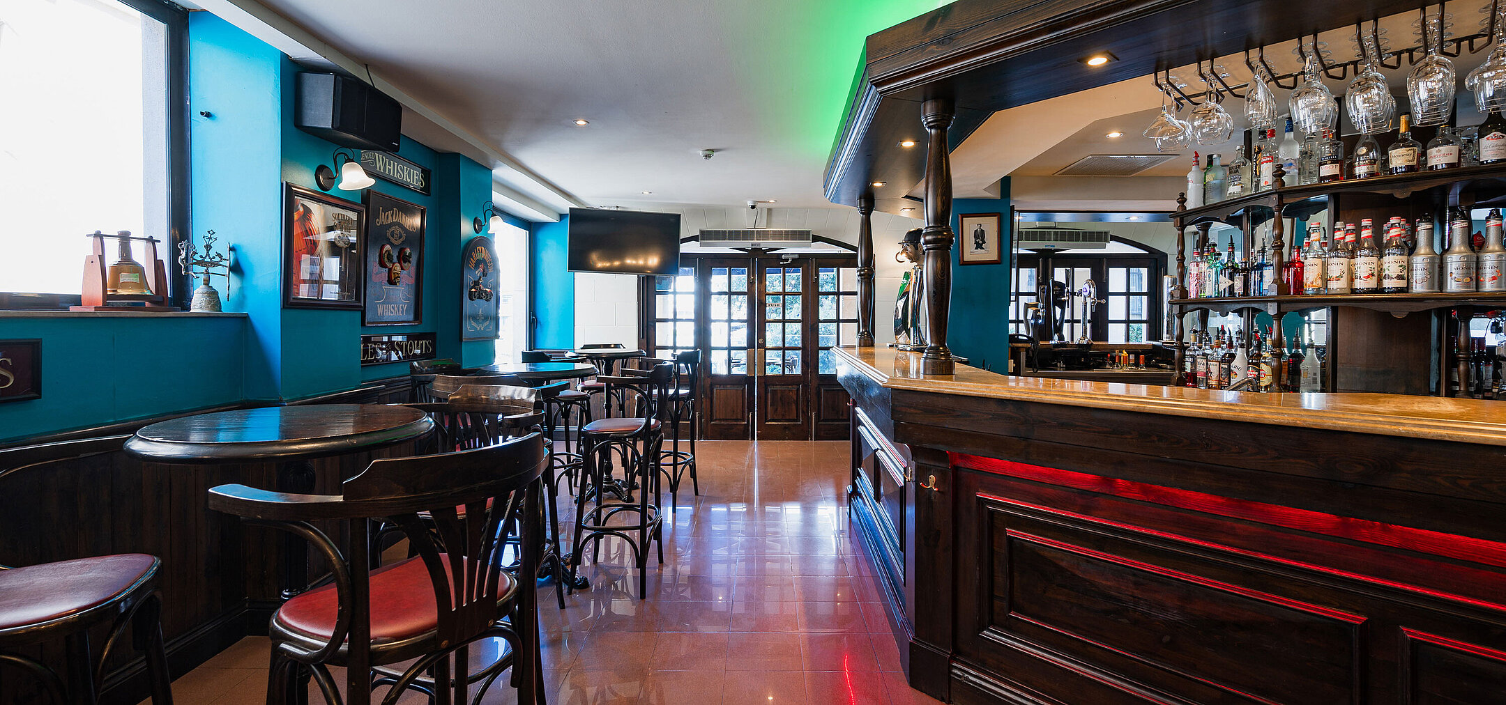 Stylish pub bar at Maritim Antonine Hotel & Spa Malta featuring dark wood interiors, a selection of spirits and cosy seating areas.