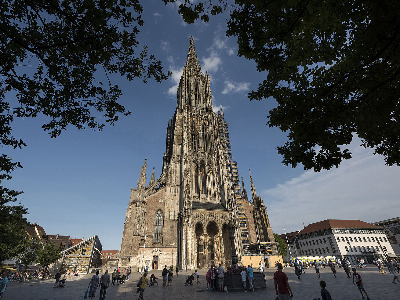 View of the impressive Ulm Minster, the tallest church in the world, with people on Münsterplatz.