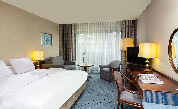 Comfort room at Maritim Hotel Cologne with a double bed, desk, sofa, and modern interior with large windows.