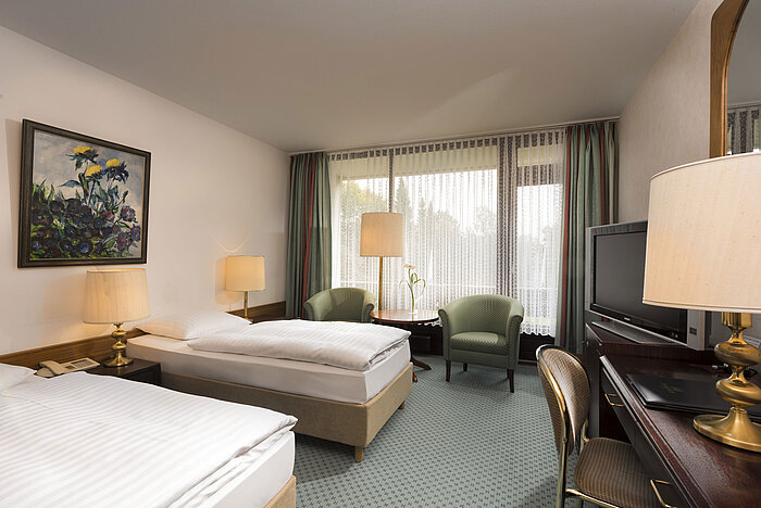 Double room with two beds, armchairs, desk and balcony at Maritim Hotel Bad Salzuflen