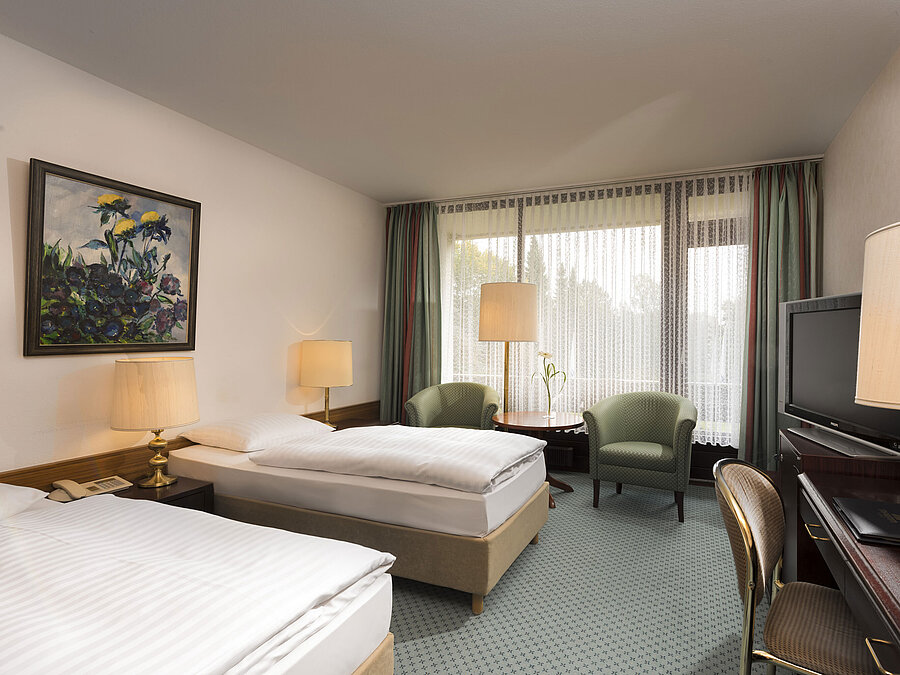 Double room with two beds, armchairs, desk and balcony at Maritim Hotel Bad Salzuflen