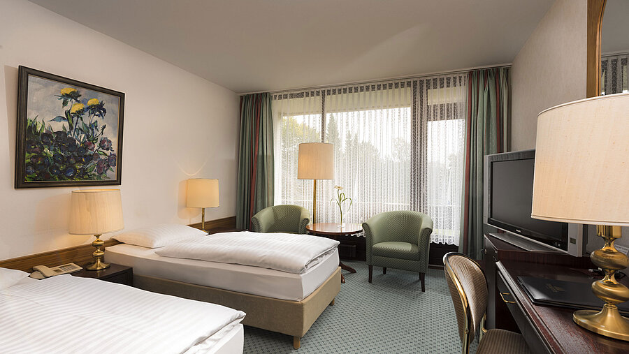 Double room with two beds, armchairs, desk and balcony at Maritim Hotel Bad Salzuflen