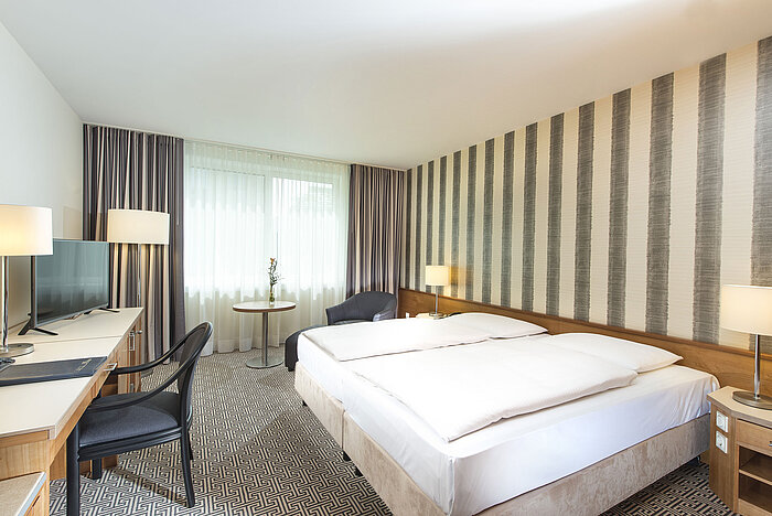 Modern hotel room with striped wall, double bed and desk at Maritim Hotel Stuttgart