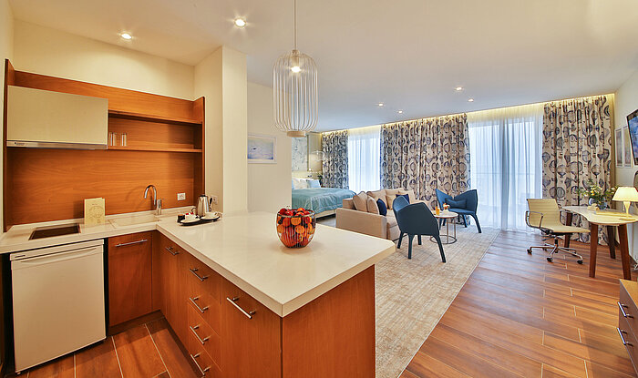 Bright studio with kitchenette, seating area and large bed in a modern hotel