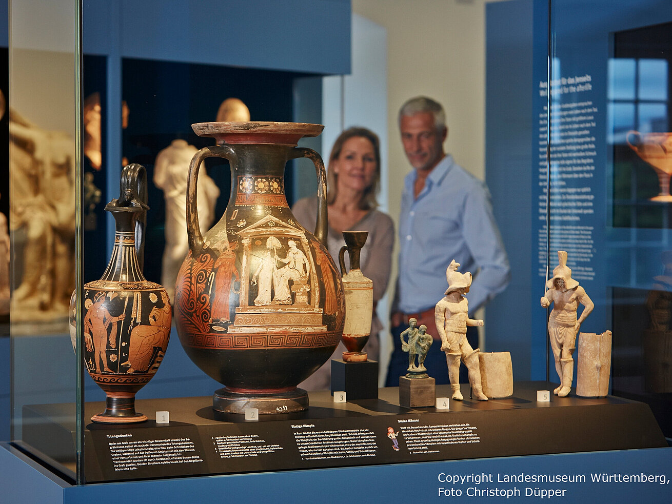 Ancient Greek vases and sculptures displayed in modern museum case