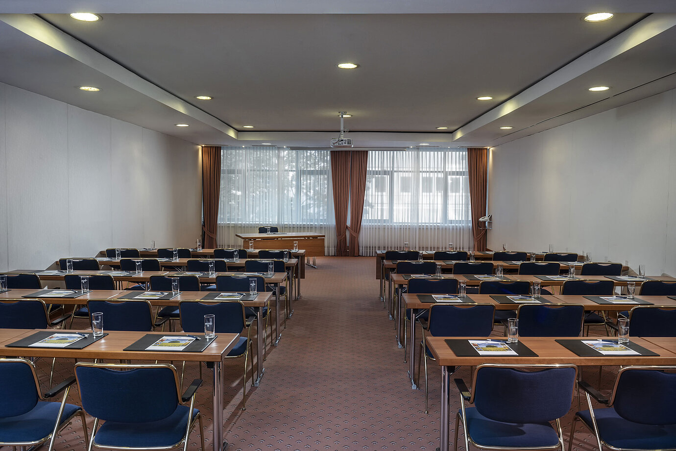Modern meeting room at the Maritim Hotel Magdeburg with row seating, natural light, and technical equipment.