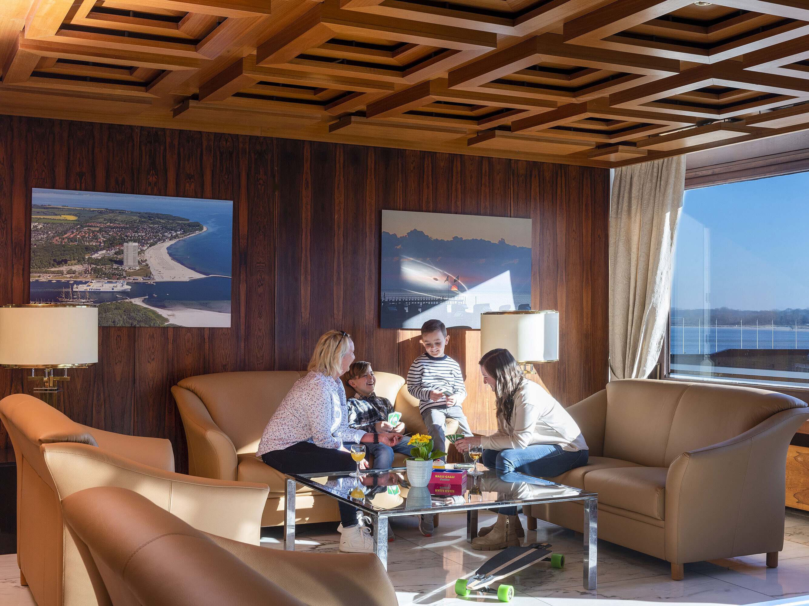 Two adults and two kids relaxing in the lounge with Baltic Sea view at Maritim Hotel Travemünde
