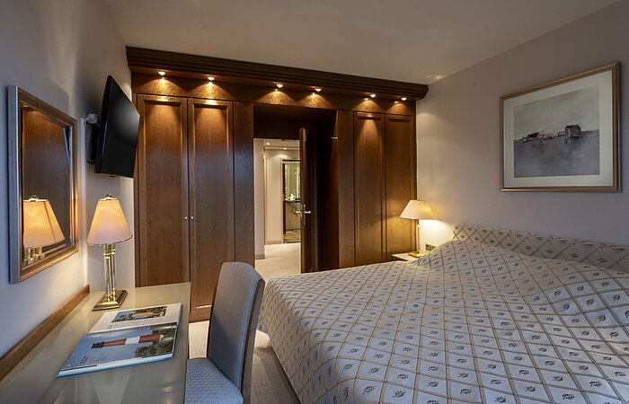 Elegant presidential suite at Maritim Hotel Kiel with large bed, desk, and warm wooden decor.