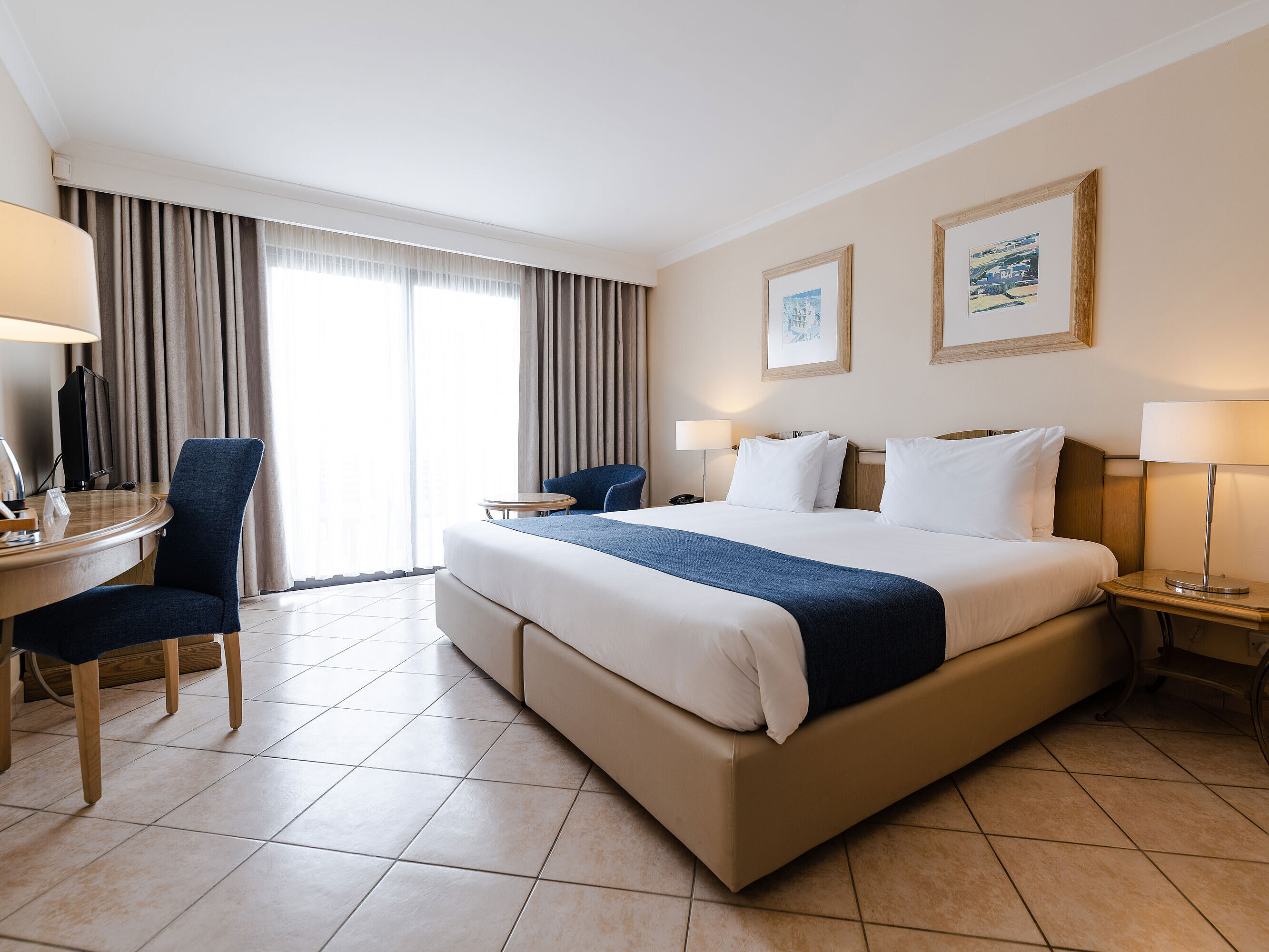 Bright double room with balcony, desk, seating area and floor-to-ceiling window