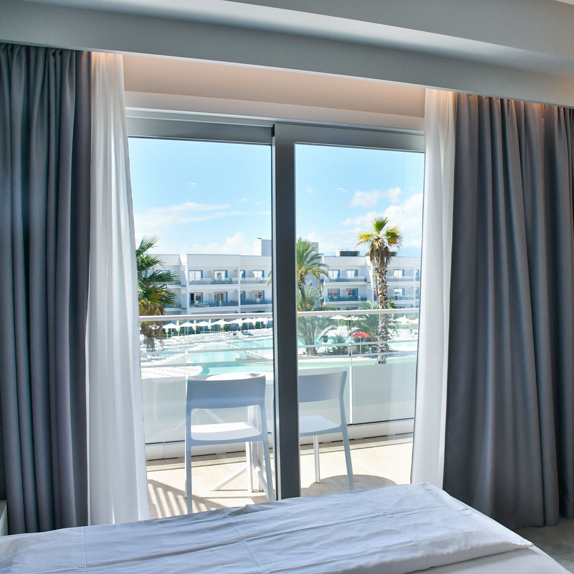 Modern hotel room with balcony and direct view of the pool at Maritim Resort Calabria