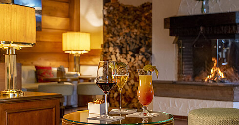 Wine, beer and cocktail on a table in front of the cosy fireplace at the Maritim Hotel Titisee bar