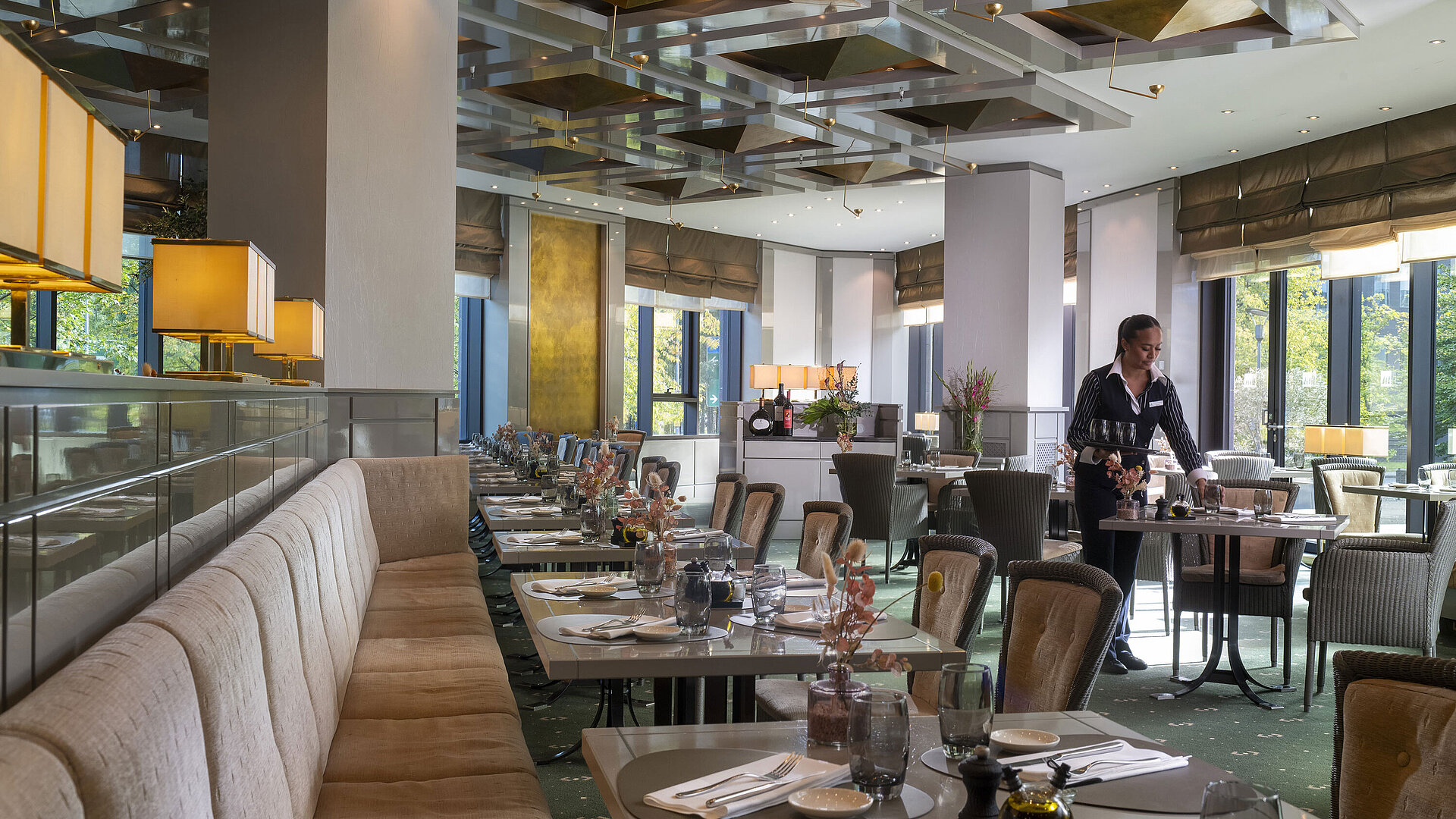 Stylish restaurant at Maritim Hotel Düsseldorf with set tables and a waitress.