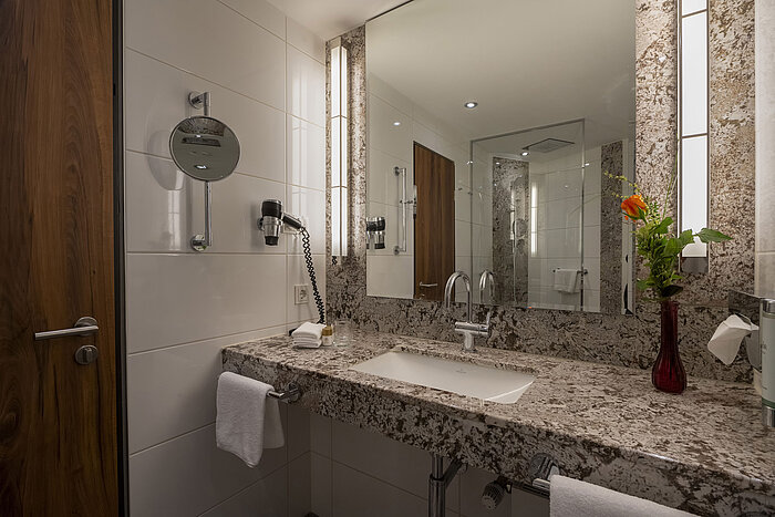 Modern bathroom at Maritim Hotel Bad Homburg with granite sink, mirror, and stylish lighting.