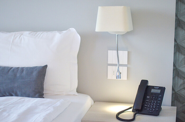 Close-up of nightstand at Maritim Resort Calabria with phone and LED reading lamp