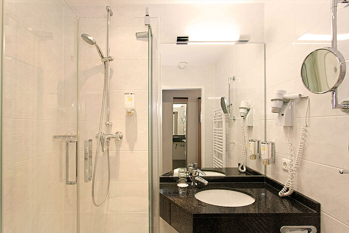 Modern bathroom with shower, washbasin and mirror at Hansa Hotel Wiesbaden