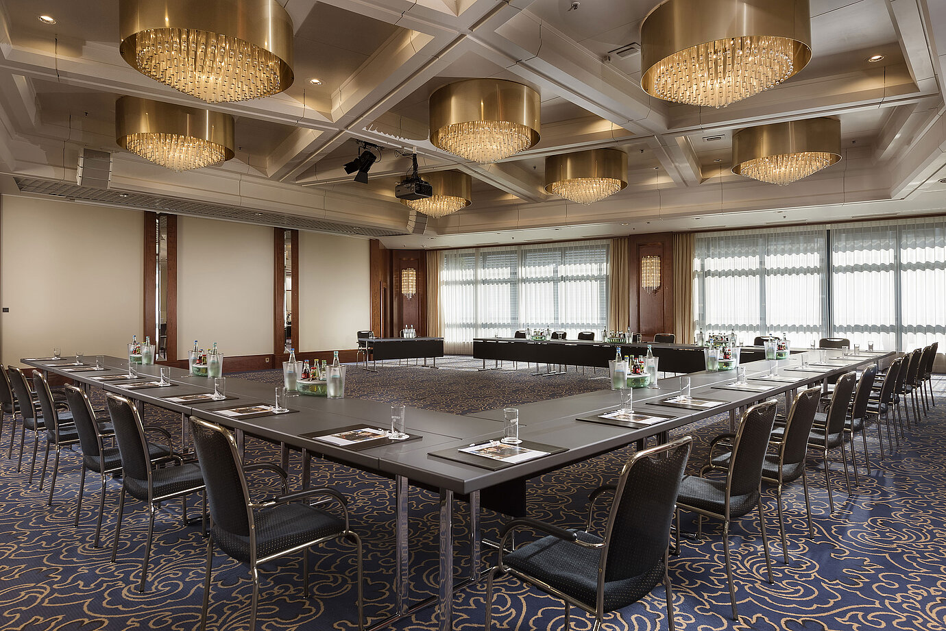 Elegant conference hall with U-shaped seating, chandeliers, and modern equipment at Maritim Hotel Hannover.