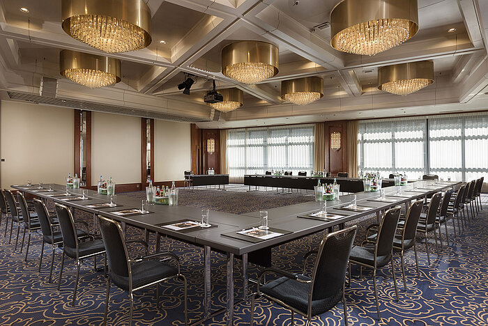 Elegant conference hall with U-shaped seating, chandeliers, and modern equipment at Maritim Hotel Hannover.
