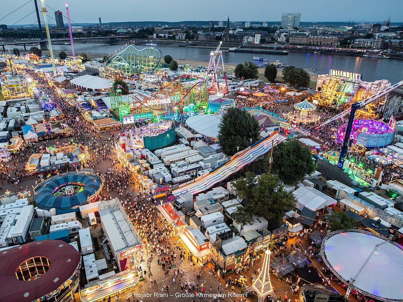 Aerial view of Rheinkirmes Düsseldorf fair with colourful rides crowds and Rhine river skyline