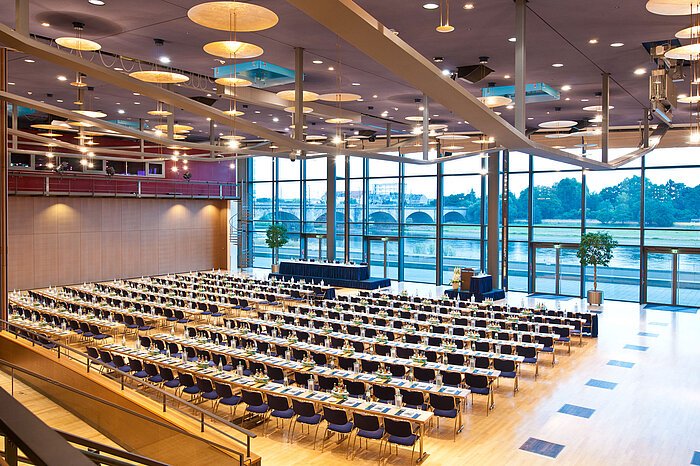 Large conference hall in Maritim Hotel Dresden with rows of blue chairs and a view of the Elbe River.